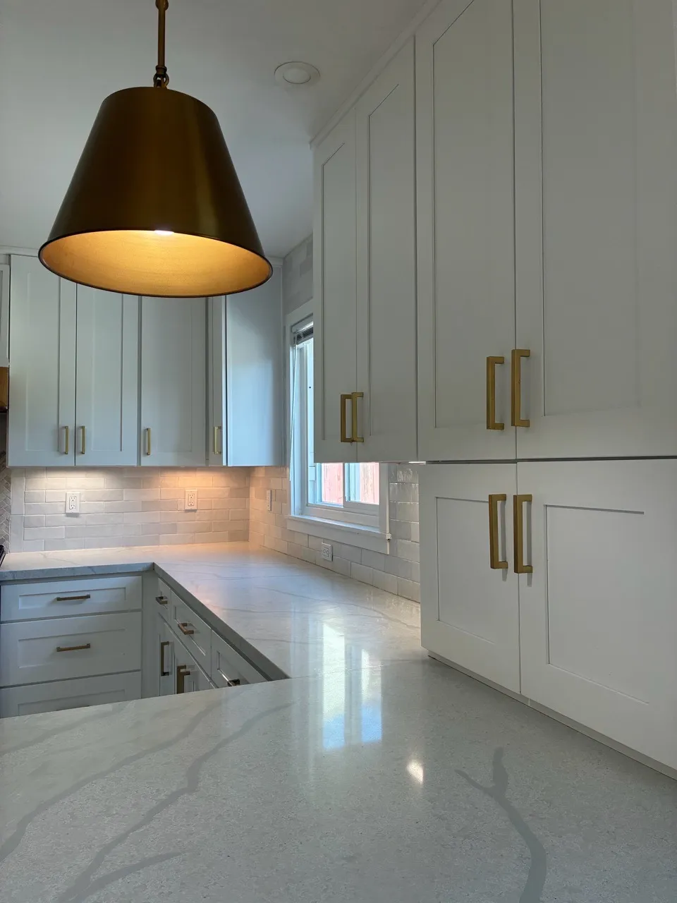 Kitchen with pale counters, white cabinets and brass hardware