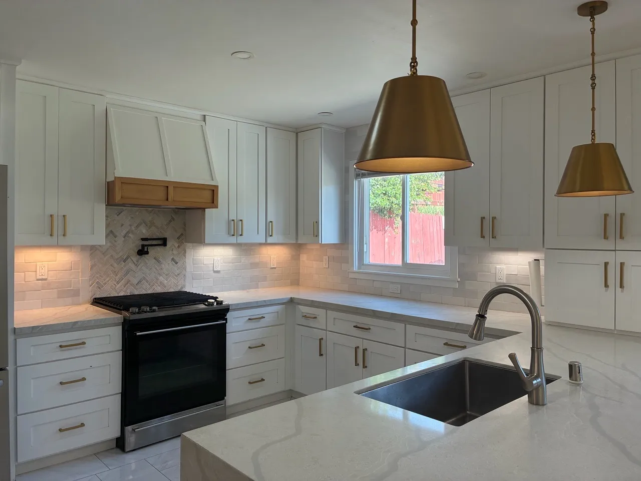 White kitchen with island, sink and warm pendant lights