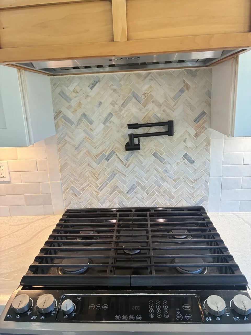 Dark cooktop beneath a patterned stone backsplash