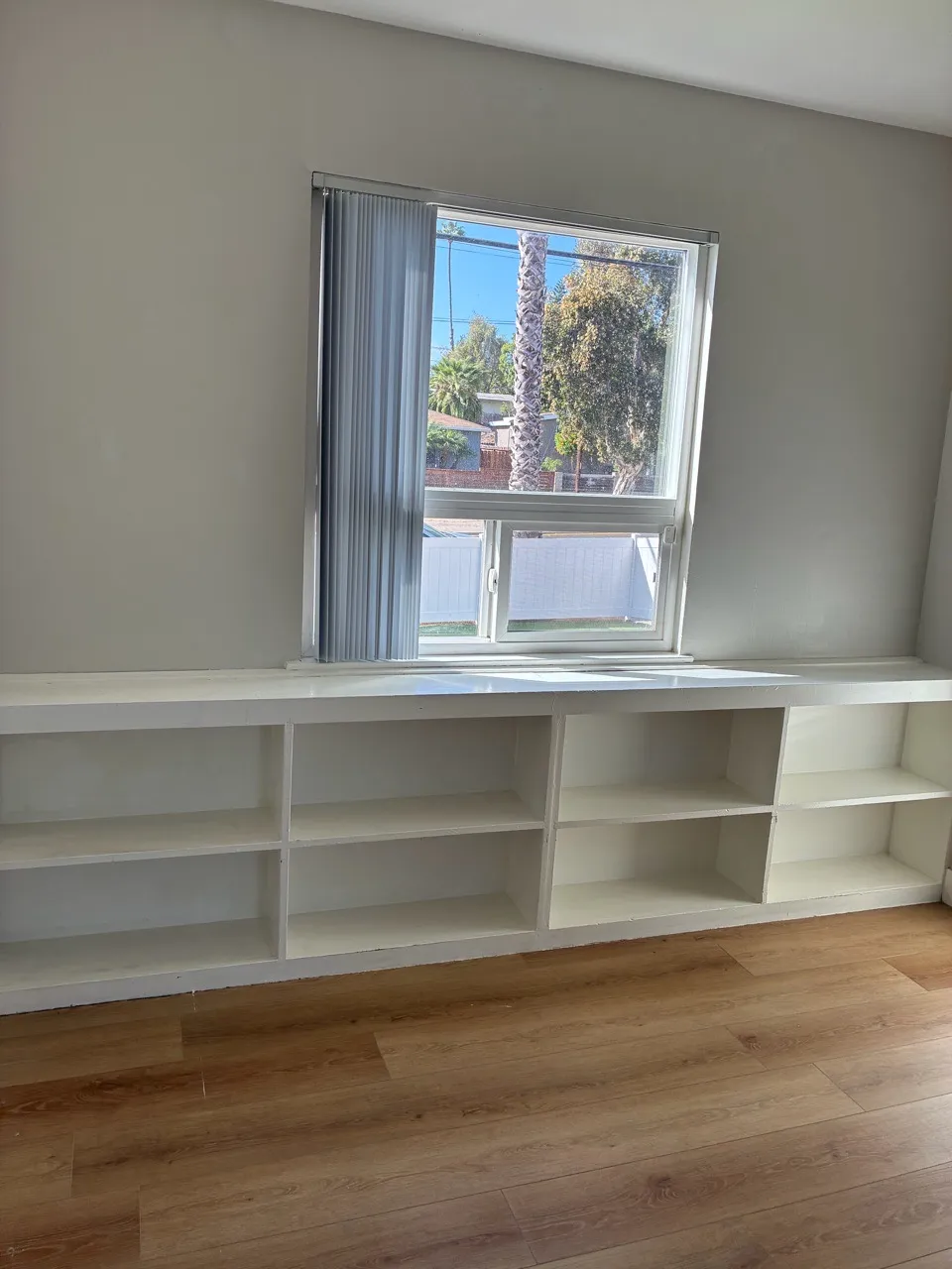 Bright empty room with built-in shelves below a window