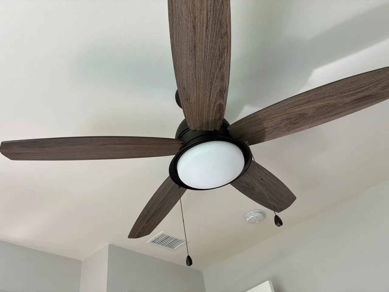Wooden ceiling fan against a white ceiling
