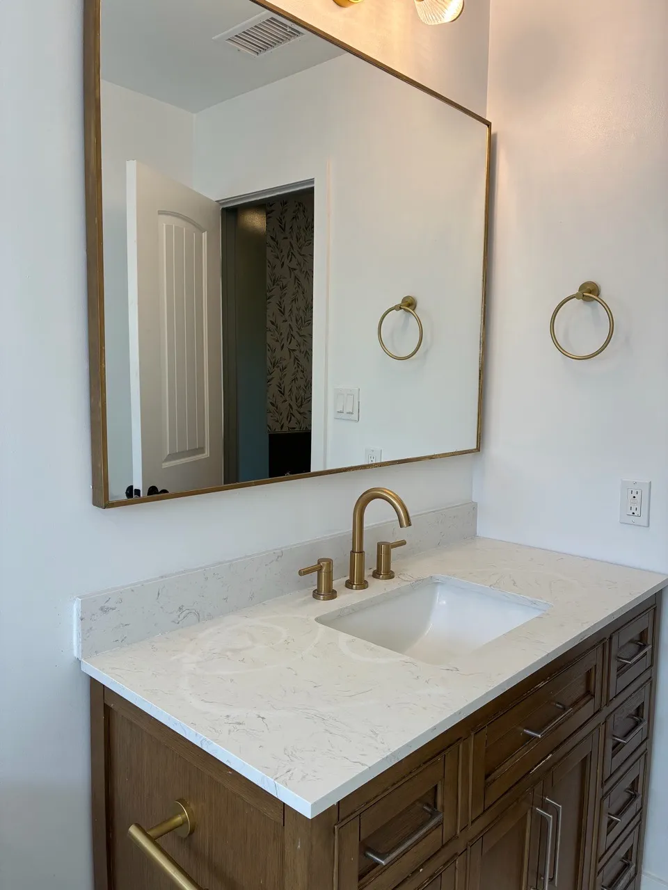 Bathroom vanity with brass faucet and large mirror