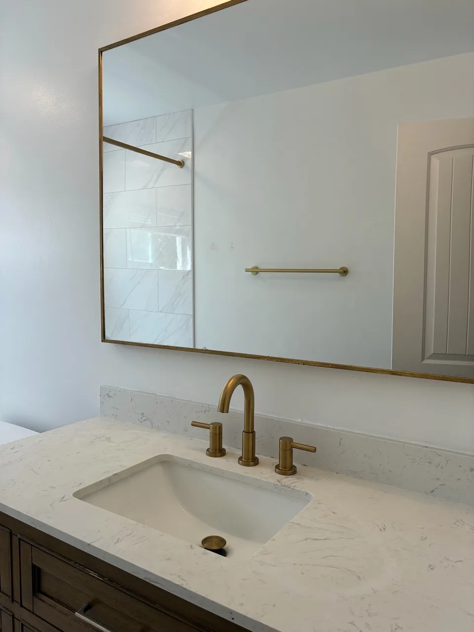 White bathroom vanity with gold-toned faucet and mirror