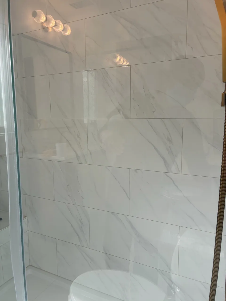 Marble-look tiled shower wall behind glass